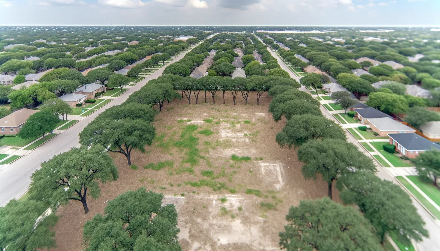 Aerial view of a cleared vacant lot bordered by trees